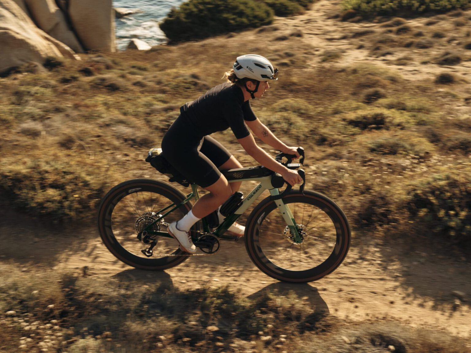 Renster op de groene Colnago G5-X op een gravelpad langs de kust