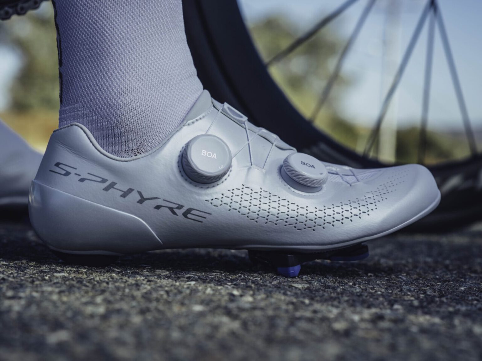 Witte Shimano S-PHYRE SH-RC910-wielrenschoen met twee BOA-draaiknoppen op een pedaal
